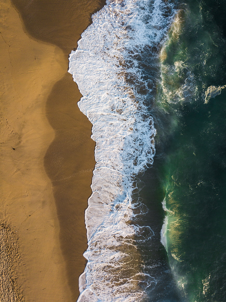 Aerial View of Ocean Waves Crashing on Sandy Beach