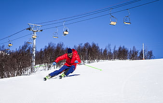 Man Skiing Down Slope with Chairlift Background