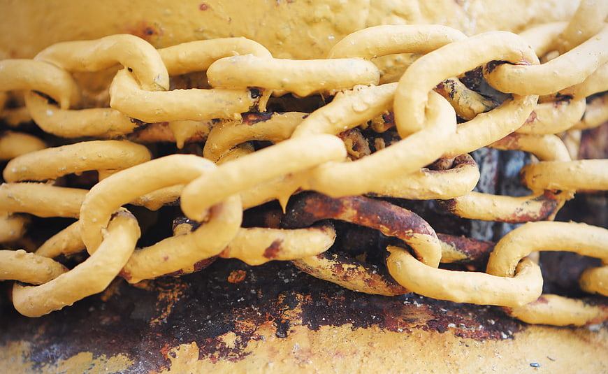 Close-up of heavy yellow industrial chains with rust