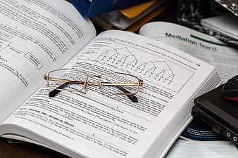 Study setup with eyeglasses on open textbook and laptop