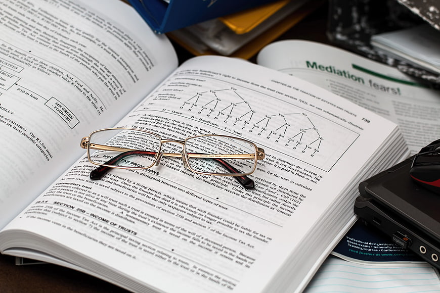 Study setup with eyeglasses on open textbook and laptop