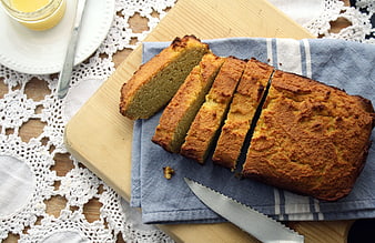 Sliced homemade loaf cake on wooden board with butter