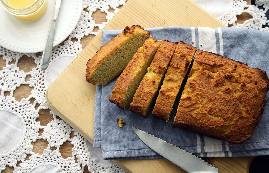 Sliced homemade loaf cake on wooden board with butter