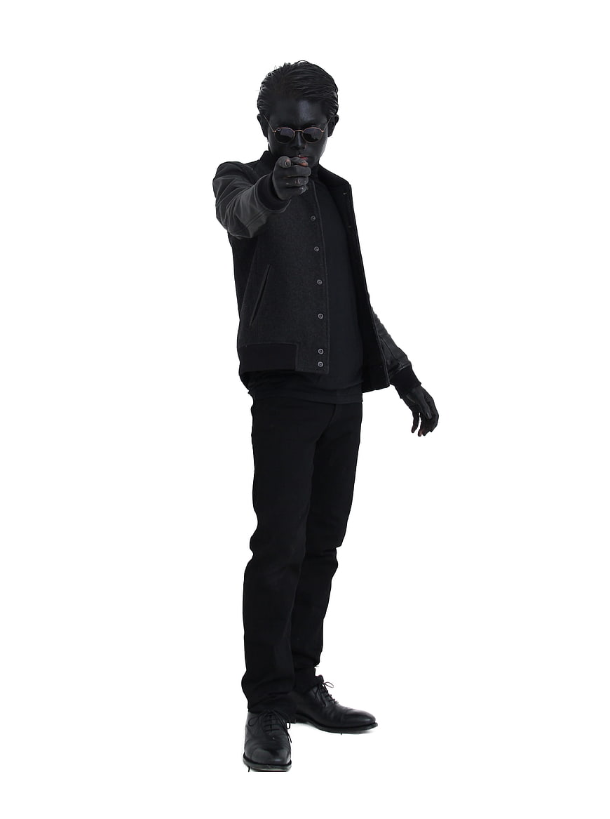 Man in all-black outfit pointing finger at camera on white background