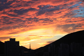 Dramatic fiery sunset over city silhouette and mountains