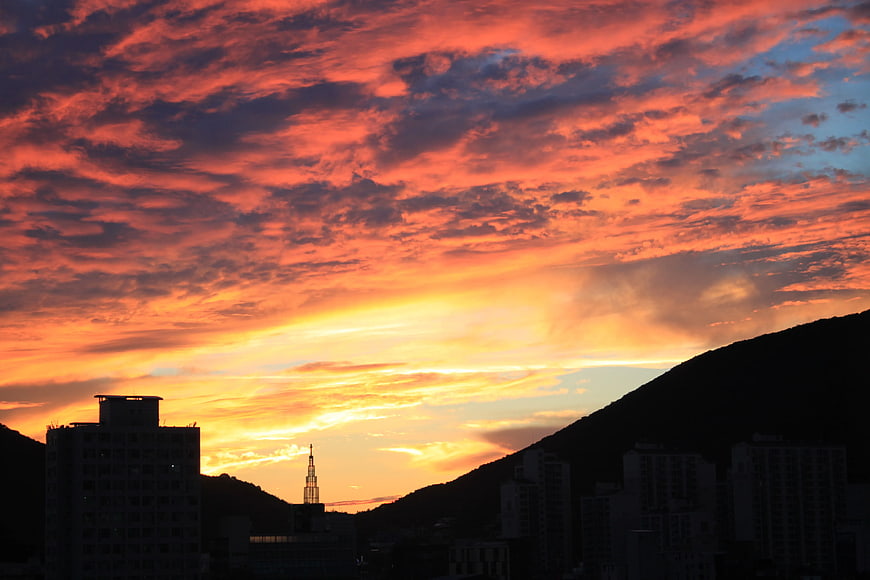Dramatic fiery sunset over city silhouette and mountains