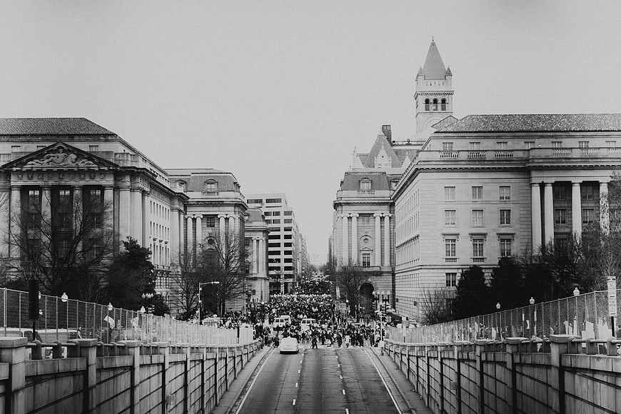 Black and white photo of crowd marching on city street