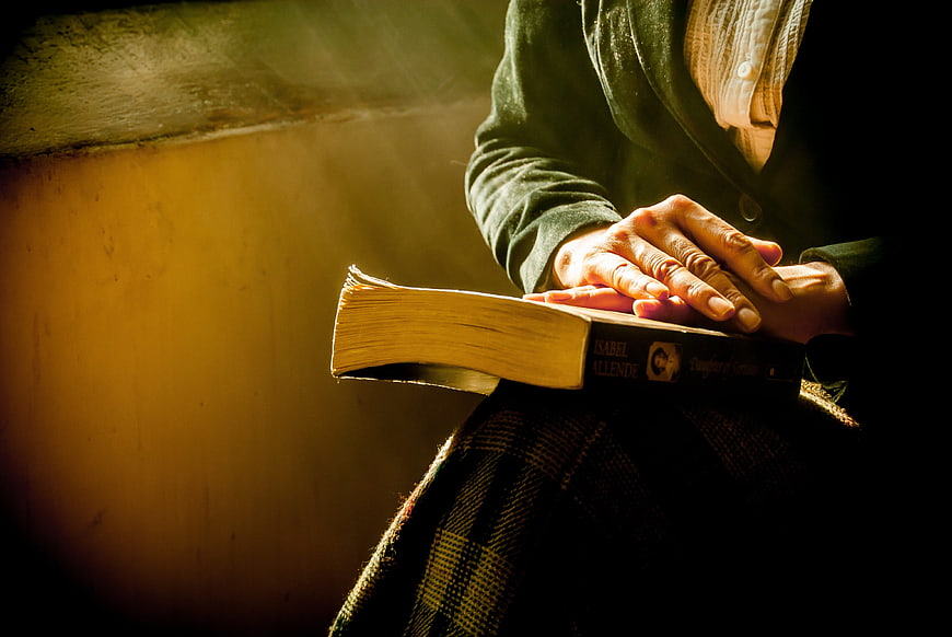 Woman holding book with warm sunlight and hands