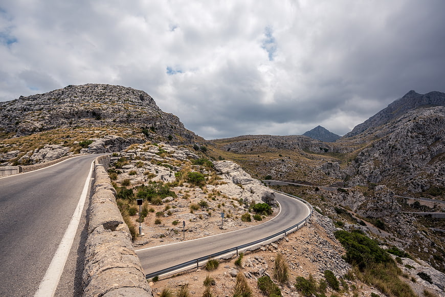 Winding Mountain Road Through Rocky Landscape Under Cloudy Sky