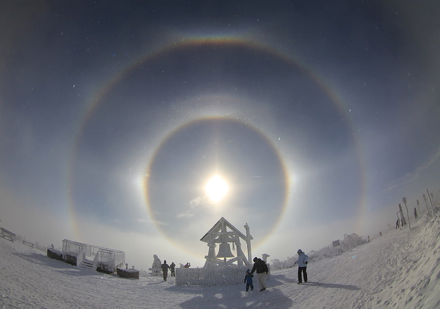 Winter Sun Halo Phenomenon Over Snowy Mountain Landscape