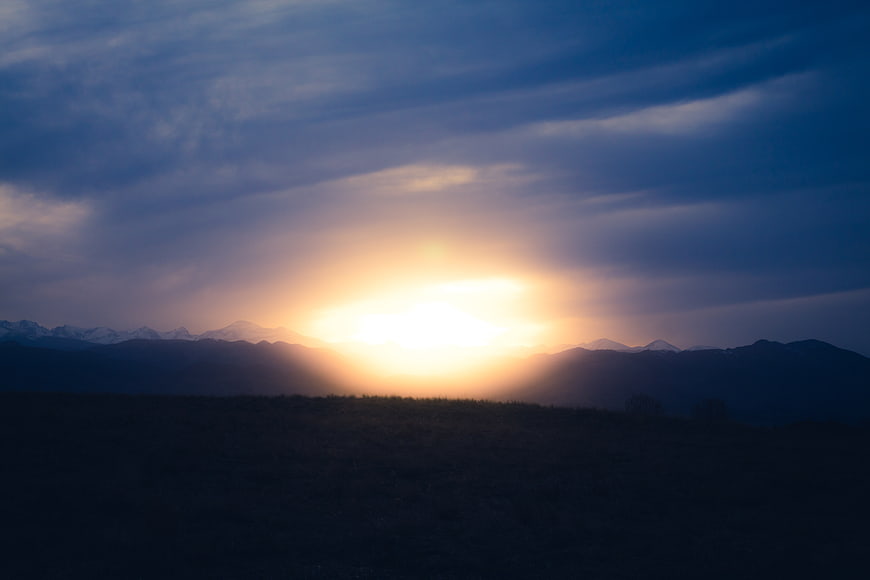 Dramatic Sunrise Over Mountain Range with Clouds