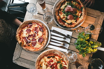 Top view of three artisan pizzas on a rustic wooden table