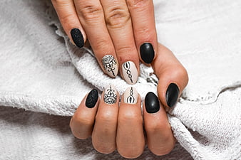 Close-up of hands with black and white geometric nail art design