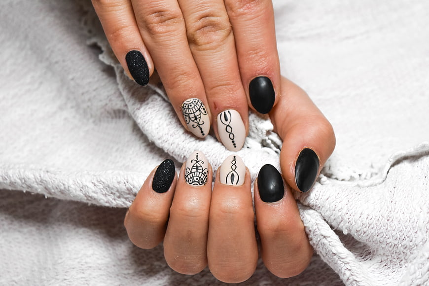 Close-up of hands with black and white geometric nail art design