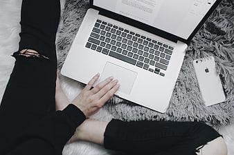 Woman using laptop on fluffy rug with smartphone