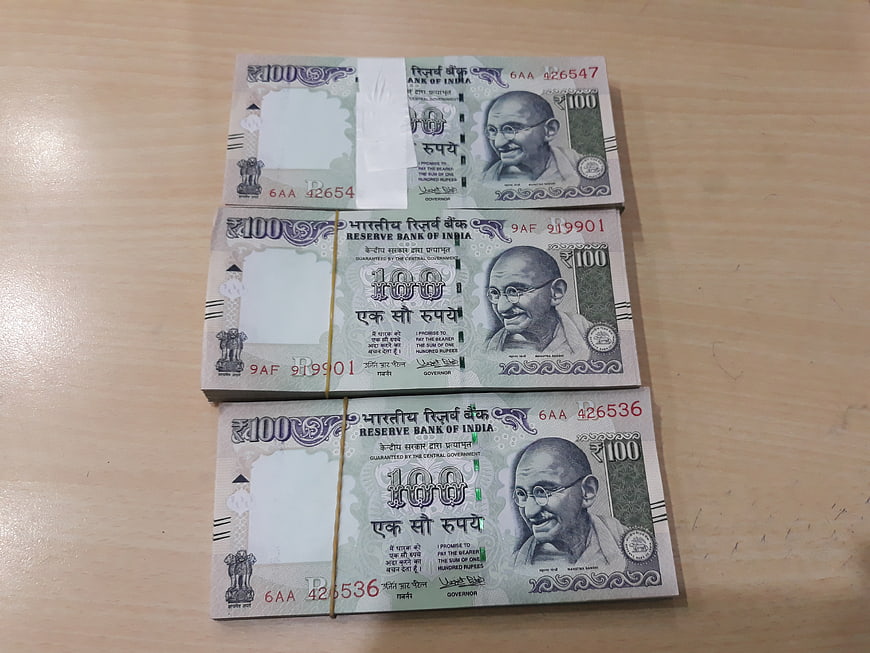 Stacks of Indian 100 Rupee Banknotes on Wooden Table