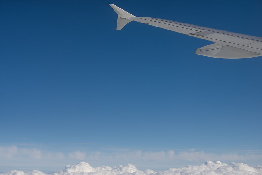 Airplane Wing Against Blue Sky and Clouds
