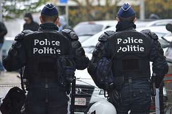 Two police officers in riot gear standing behind barbed wire