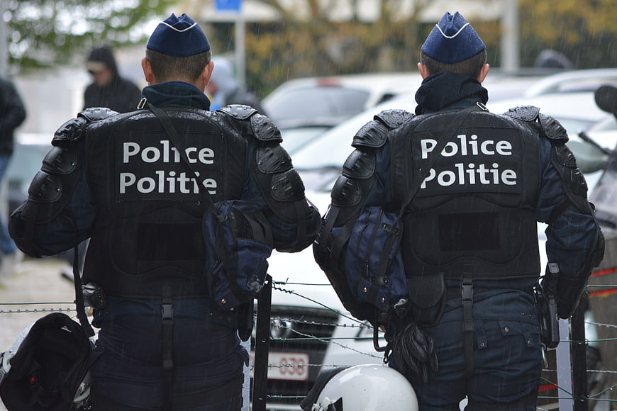 Two police officers in riot gear standing behind barbed wire