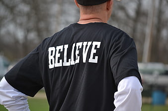 Man Wearing Black T-Shirt with Believe Text on Back