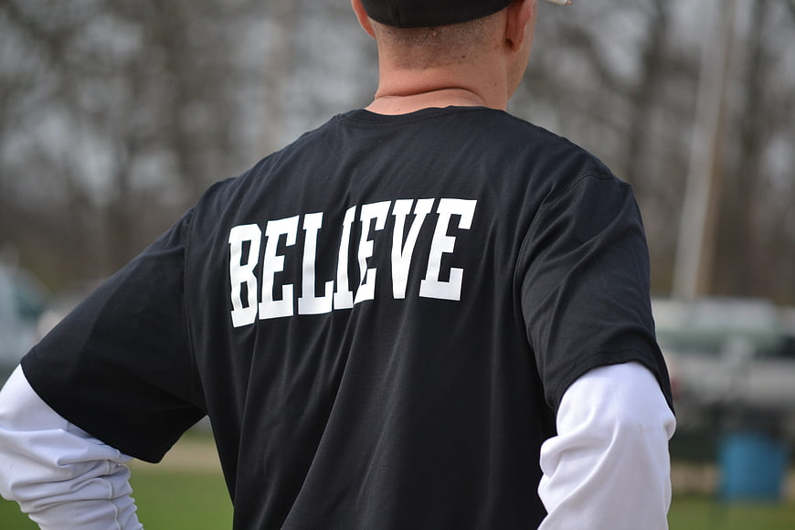 Man Wearing Black T-Shirt with Believe Text on Back