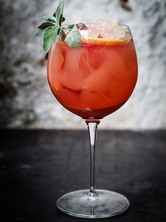Refreshing Red Cocktail with Sage and Citrus Garnish