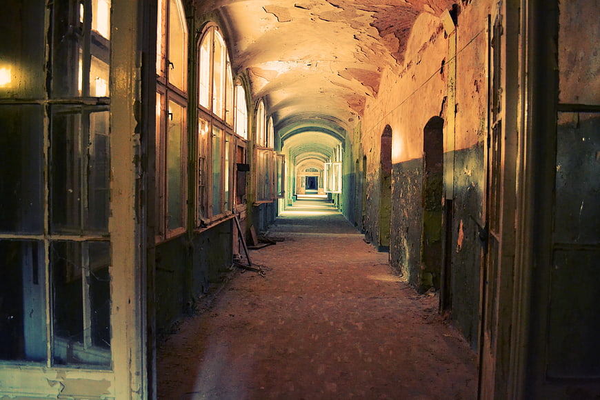 Abandoned Arched Hallway with Peeling Paint and Vintage Windows