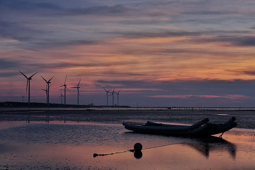 Silhouetted Wind Turbines and Canoe at Sunset
