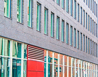 Modern brick building facade with red accent and glass windows