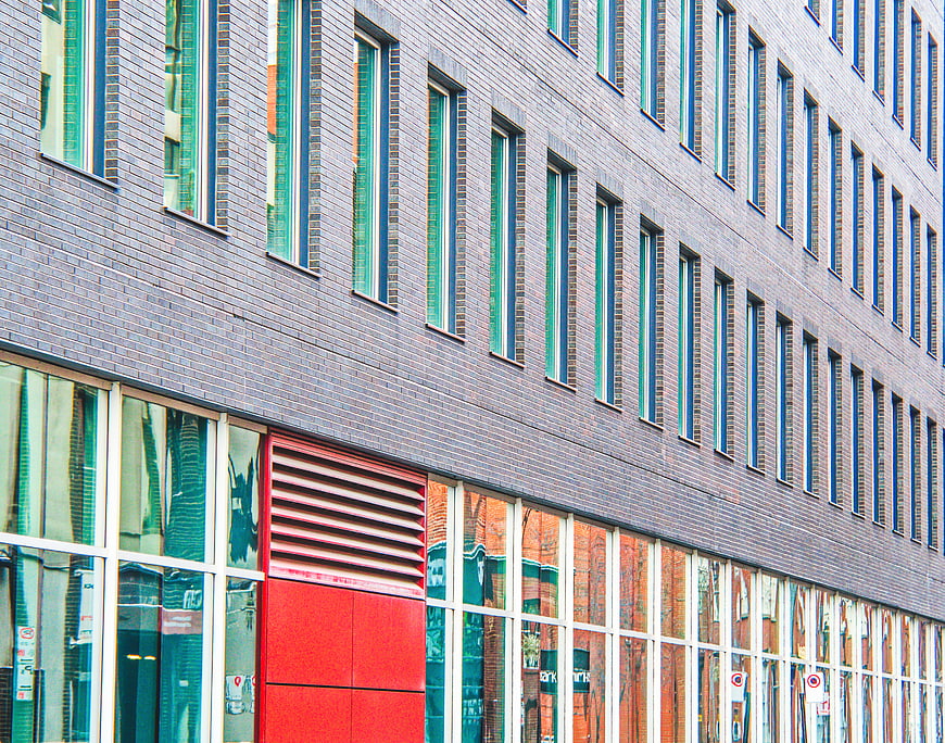 Modern brick building facade with red accent and glass windows