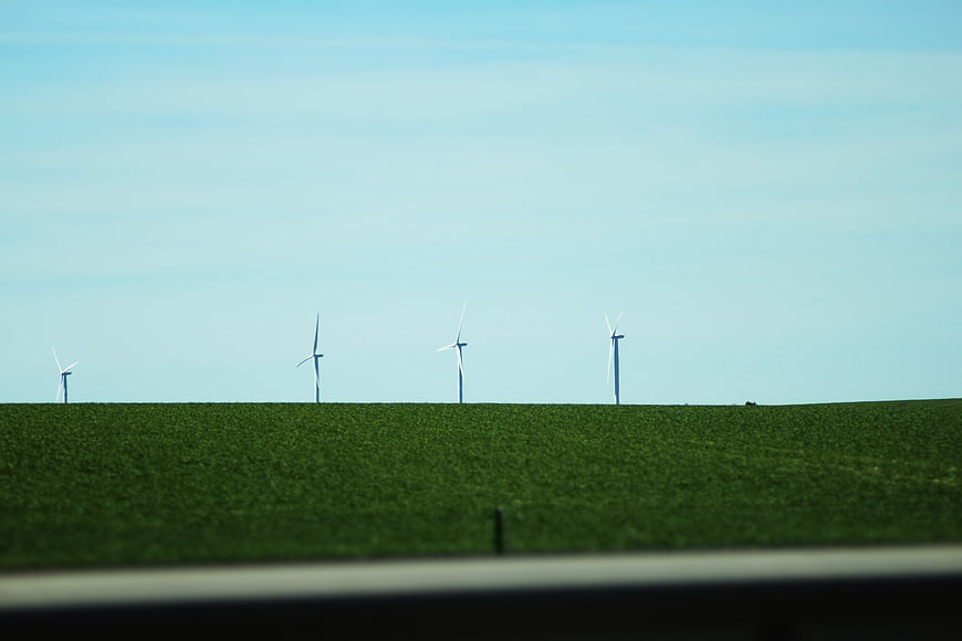 Wind turbines on green hill against blue sky