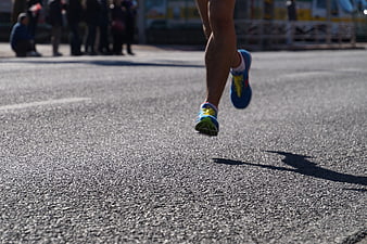 Close-up of runner's legs sprinting on asphalt road