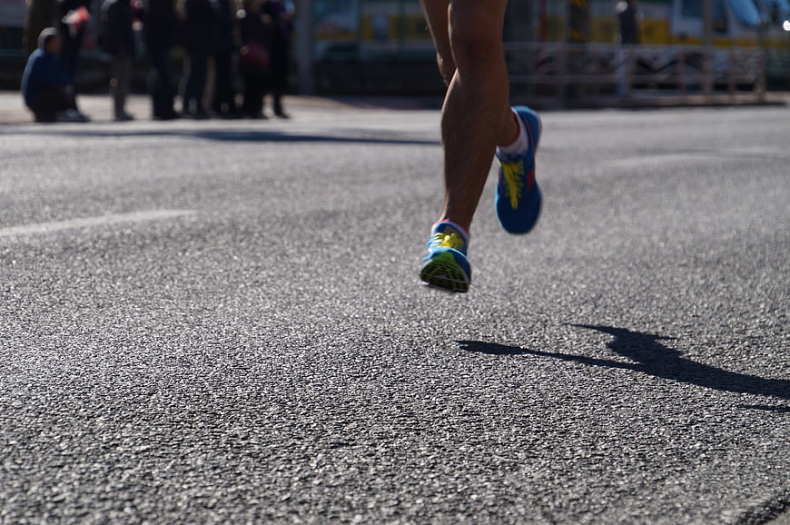 Close-up of runner's legs sprinting on asphalt road