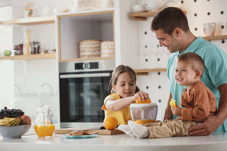 Happy family making fresh orange juice in modern kitchen