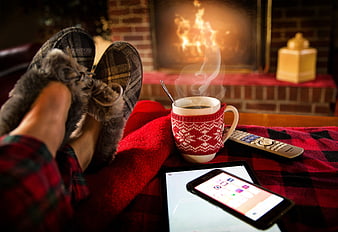 Cozy winter relaxation by fireplace with coffee and tablet