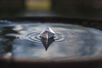 Silver Origami Boat Floating on Water with Ripples