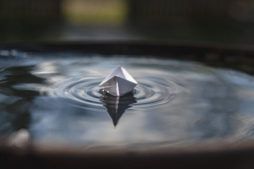 Silver Origami Boat Floating on Water with Ripples