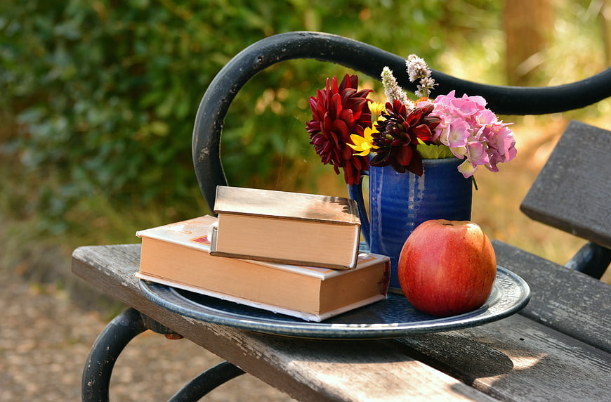 Books, Apple, and Flowers on Garden Bench