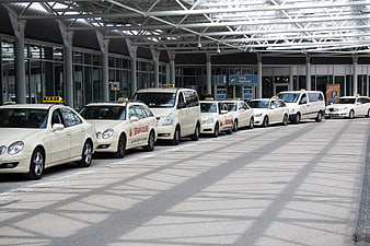 Row of white taxis parked at airport terminal taxi stand