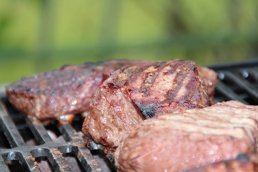 Close-up of juicy grilled steaks on outdoor barbecue grill