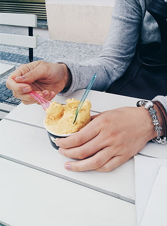 Close-up of hands eating yellow ice cream outdoors