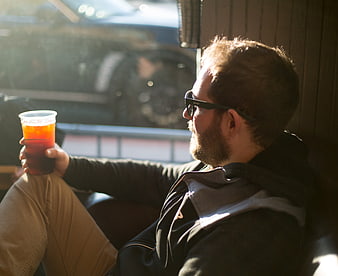 Relaxed man with beard drinking beer in sunlight