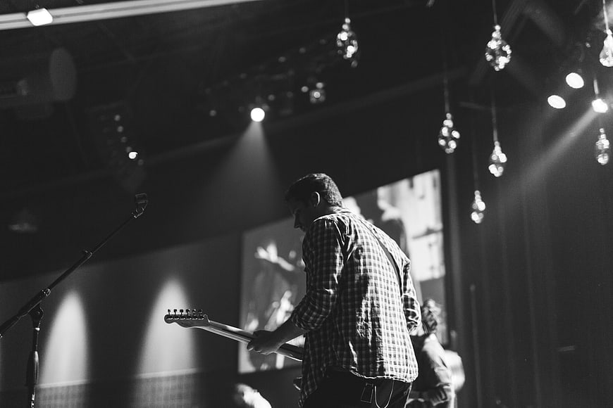 Male guitarist performing on stage in black and white