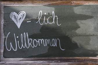 Handwritten German Welcome Message on Rustic Wooden Chalkboard