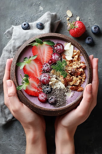 Hands Holding Berry Smoothie Bowl with Granola and Fruit