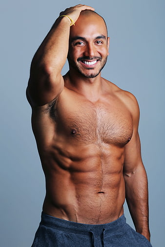 Smiling muscular man posing shirtless in studio