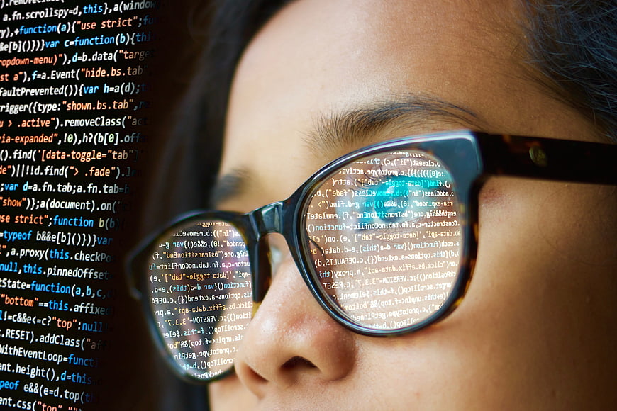 Close-up of woman wearing glasses with code reflection
