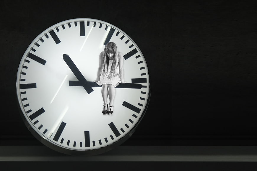 Sad girl sitting on clock hands in black and white