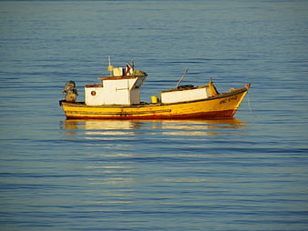 Yellow fishing boat floating on calm blue water