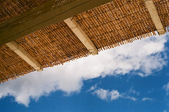 Bamboo Roof Structure Against Blue Sky with Clouds